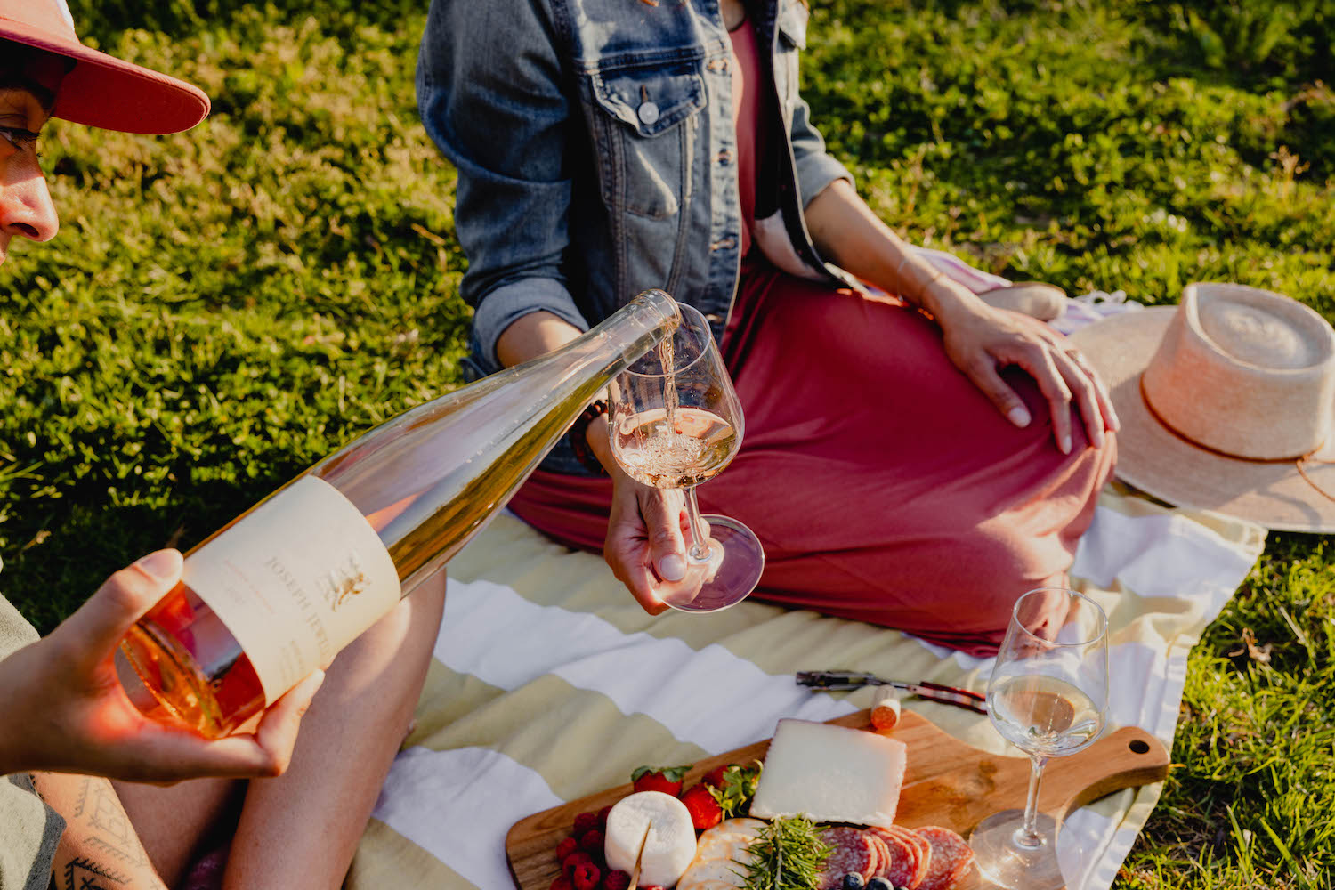 Two people having a picnic on the grass with cheese and wine in the summer