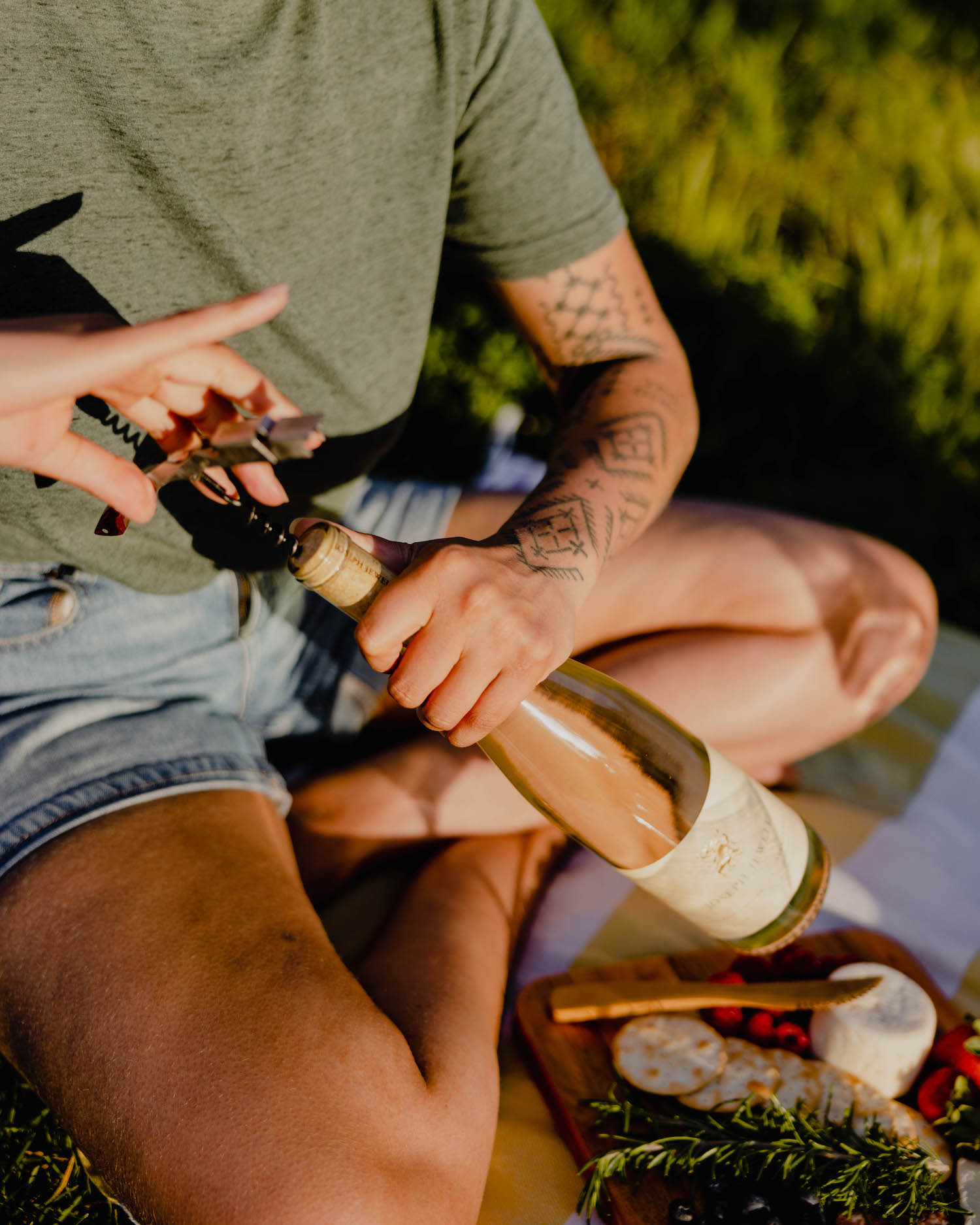 Person opening a bottle of wine, rosé and vermentino, outside in a garden setting