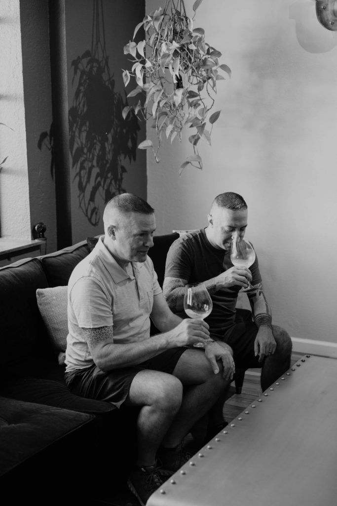 Two men drinking Chardonnay wine on a couch in a wine tasting room